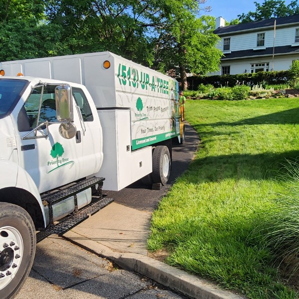 Branded Priority Tree "(513) UP-A-TREE" chipper truck parked in a driveway at a residential property
